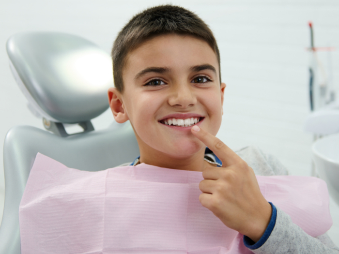boy in dentist chair pointing at tooth